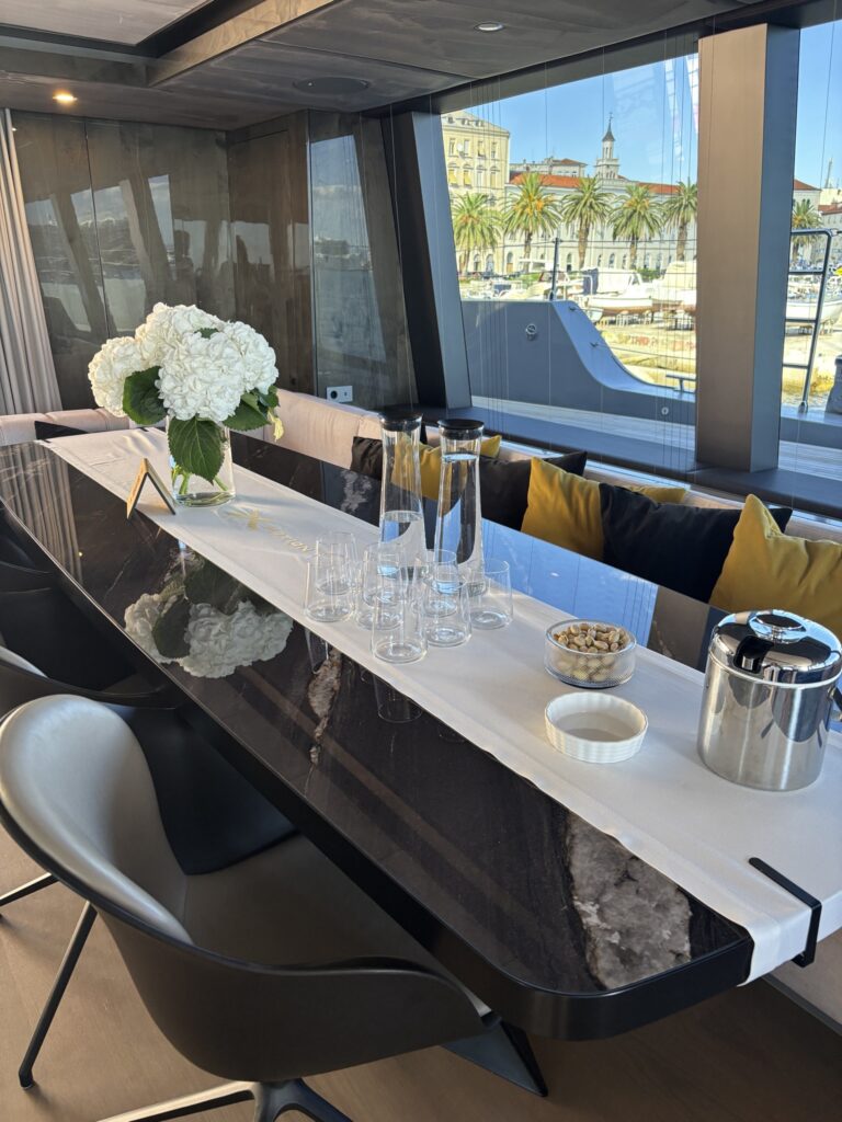 Dining table in the saloon with the Split waterfront through the glass
